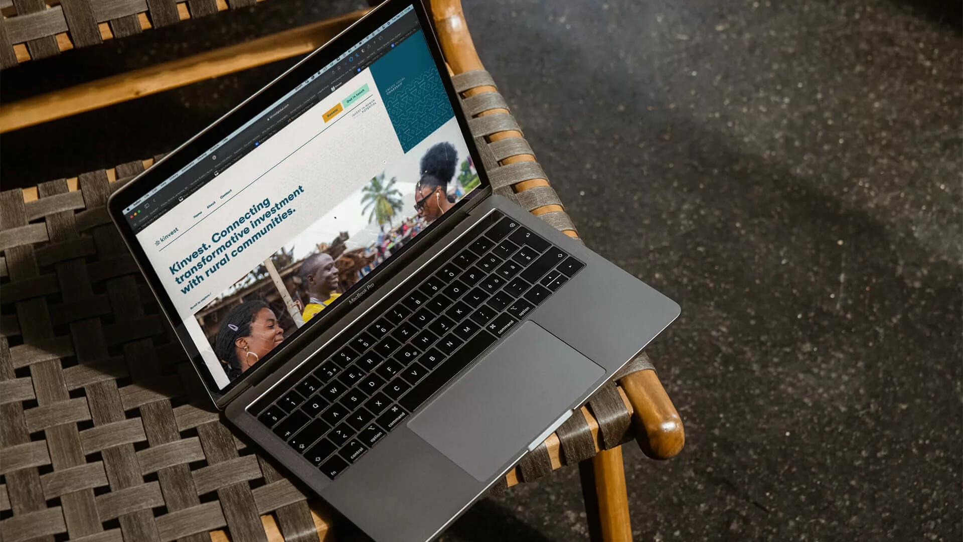 Photo of Kinvest Global website on laptop screen on a wicker chair.