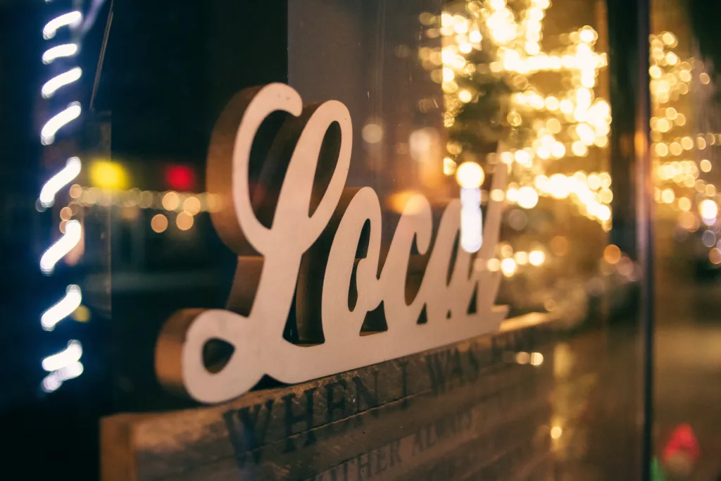 Sign "Local" with festive lights reflection.